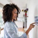 Young African American woman setting up the intelligent home system on a tablet computer - technology concepts. **DESIGN ON SCREEN WAS MADE FROM SCRATCH BY US**